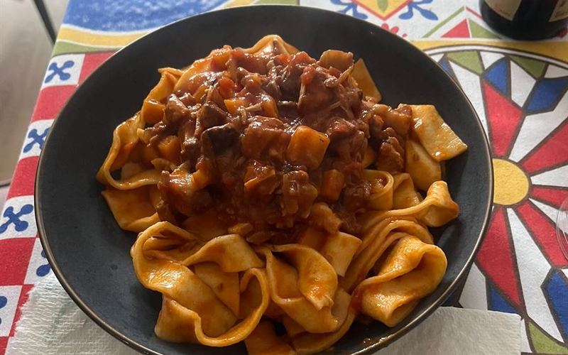 Pappardelle al ragù di Lorenzo, servite su piastrelle dipinte a mano